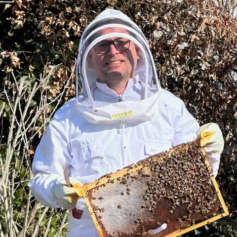 Mann mit Bienenstock und Schutzanzug